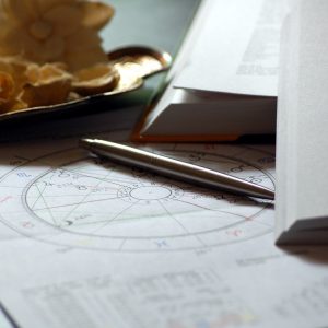 astrologický rádix na papieri, pero a otvorená kniha