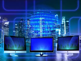 tri monitory a v pozadí mrakodrapy